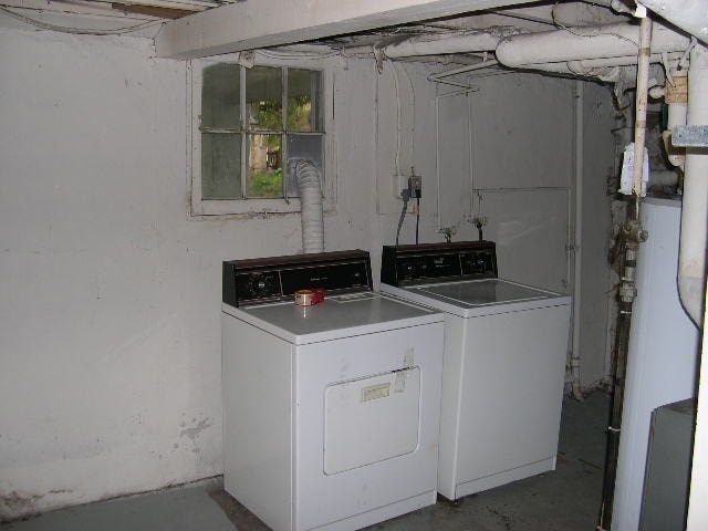 A white appliance with a black top sits in a room with a window and pipes.