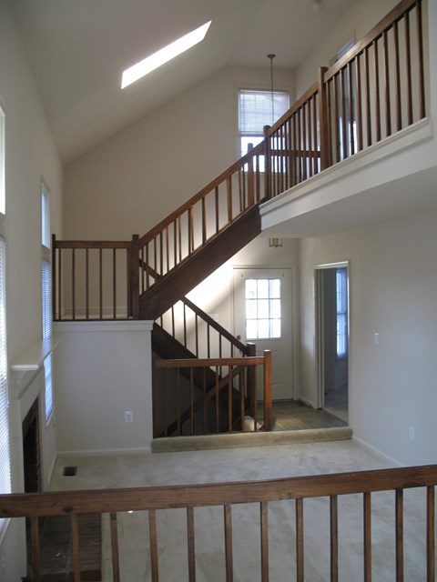A wooden staircase with a railing leads up to a second floor.