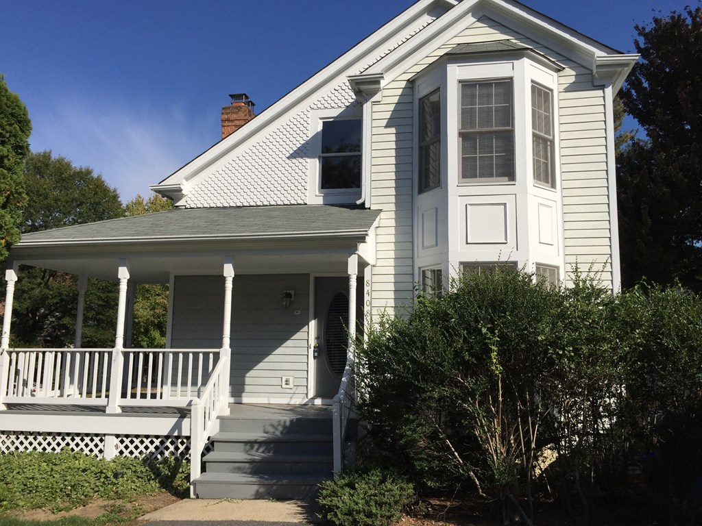 A white house with a porch and a covered entrance.