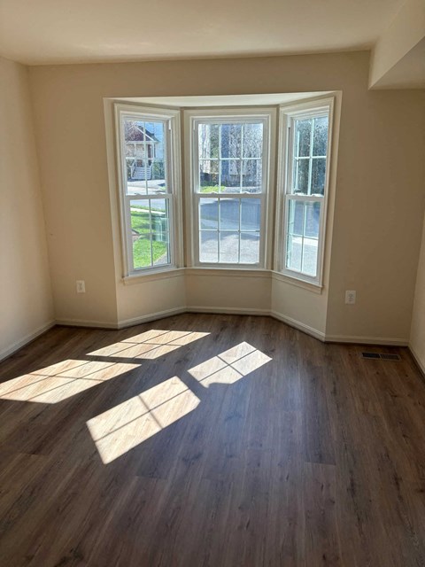 A room with a large window and wooden flooring.