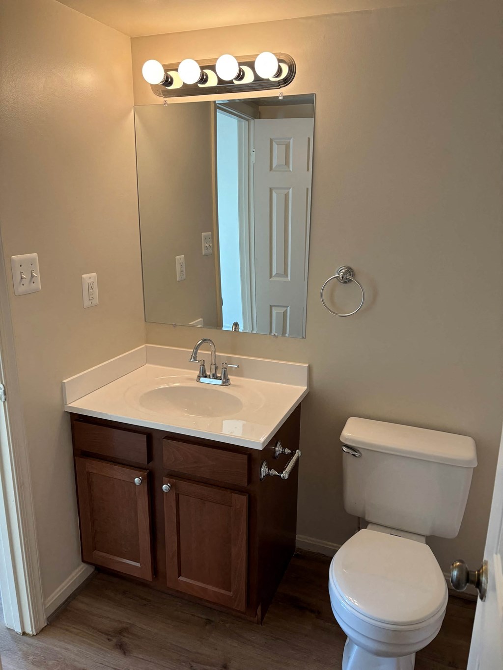 A bathroom with a white toilet, sink, and mirror.