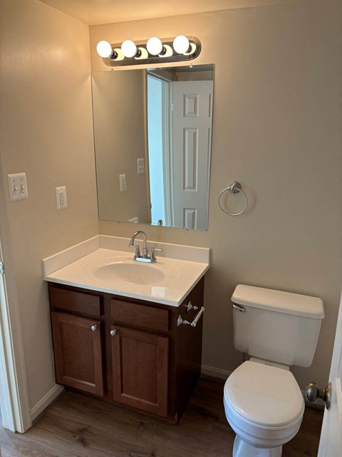 A bathroom with a white toilet, sink, and mirror.