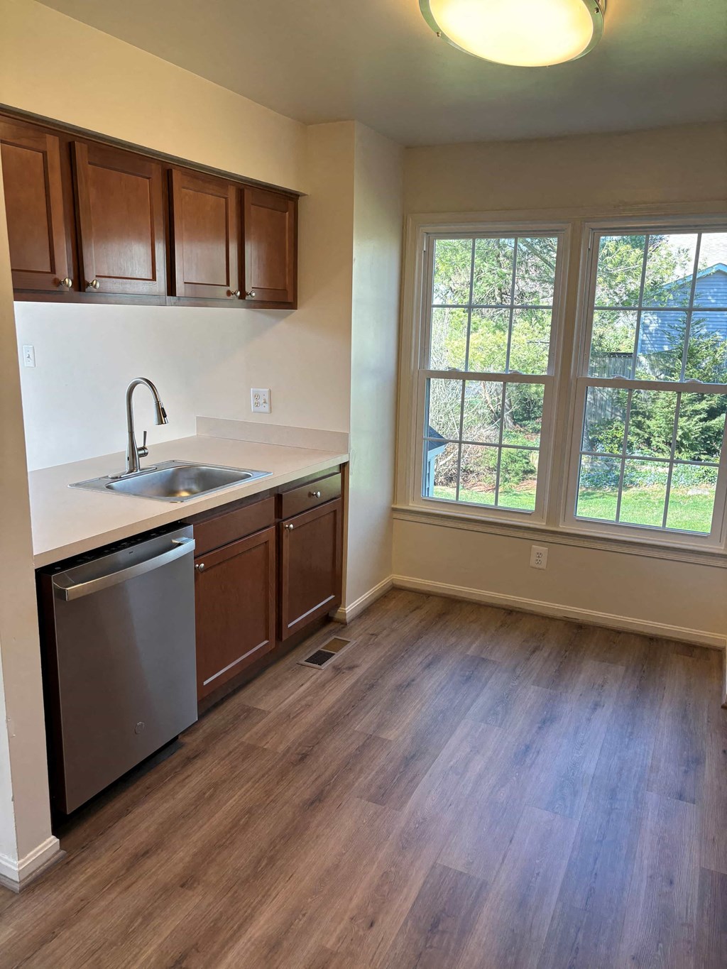 A kitchen with wooden cabinets and a stainless steel dishwasher.