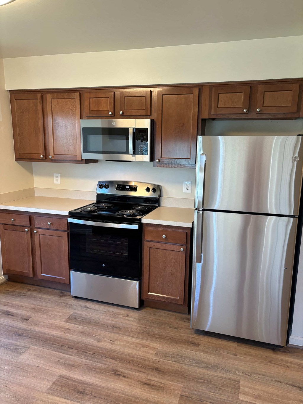A kitchen with a stove, refrigerator, and microwave.