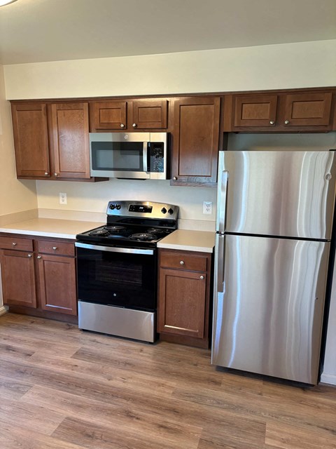 A kitchen with a stove, refrigerator, and microwave.