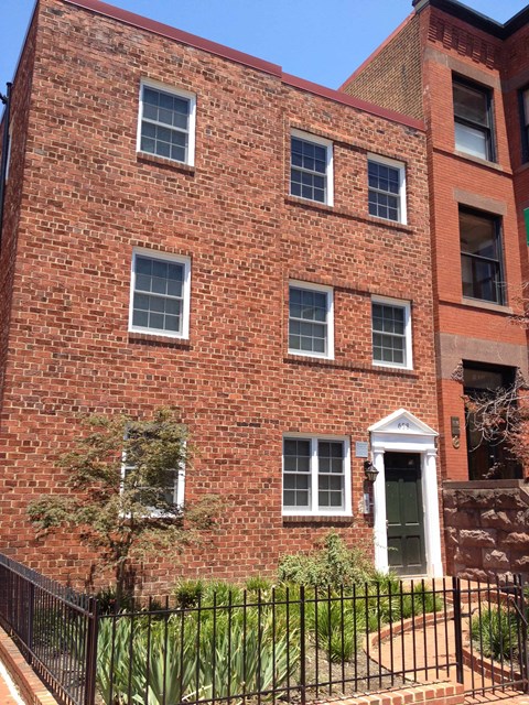 A red brick building with a black iron fence in front.
