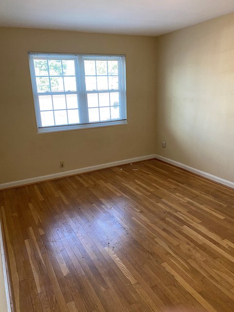 A room with a window and wooden flooring.