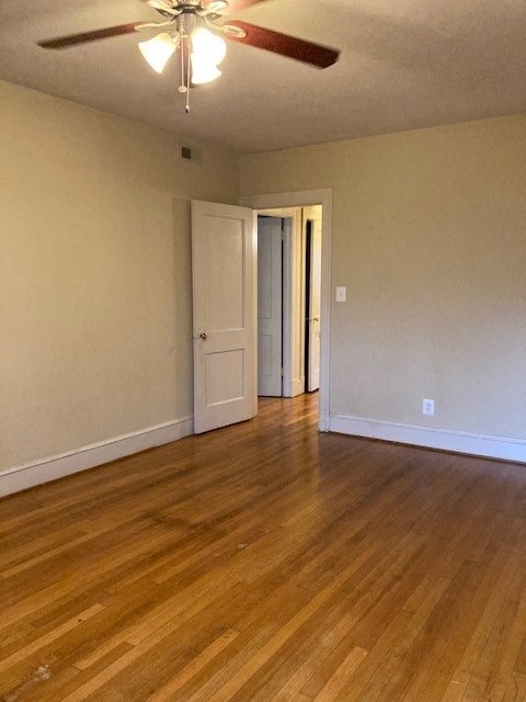 A room with a ceiling fan and wooden floors.
