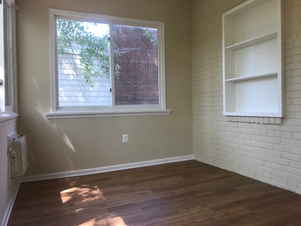 A room with a window and a white shelf on the wall.