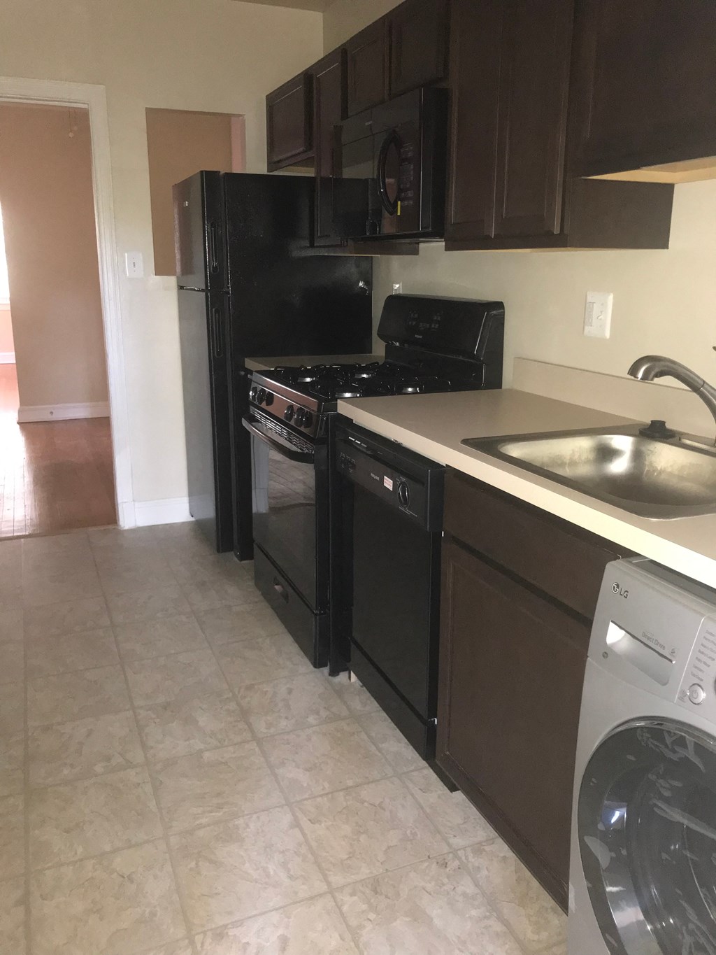 A black fridge and oven in a kitchen with brown cabinets.