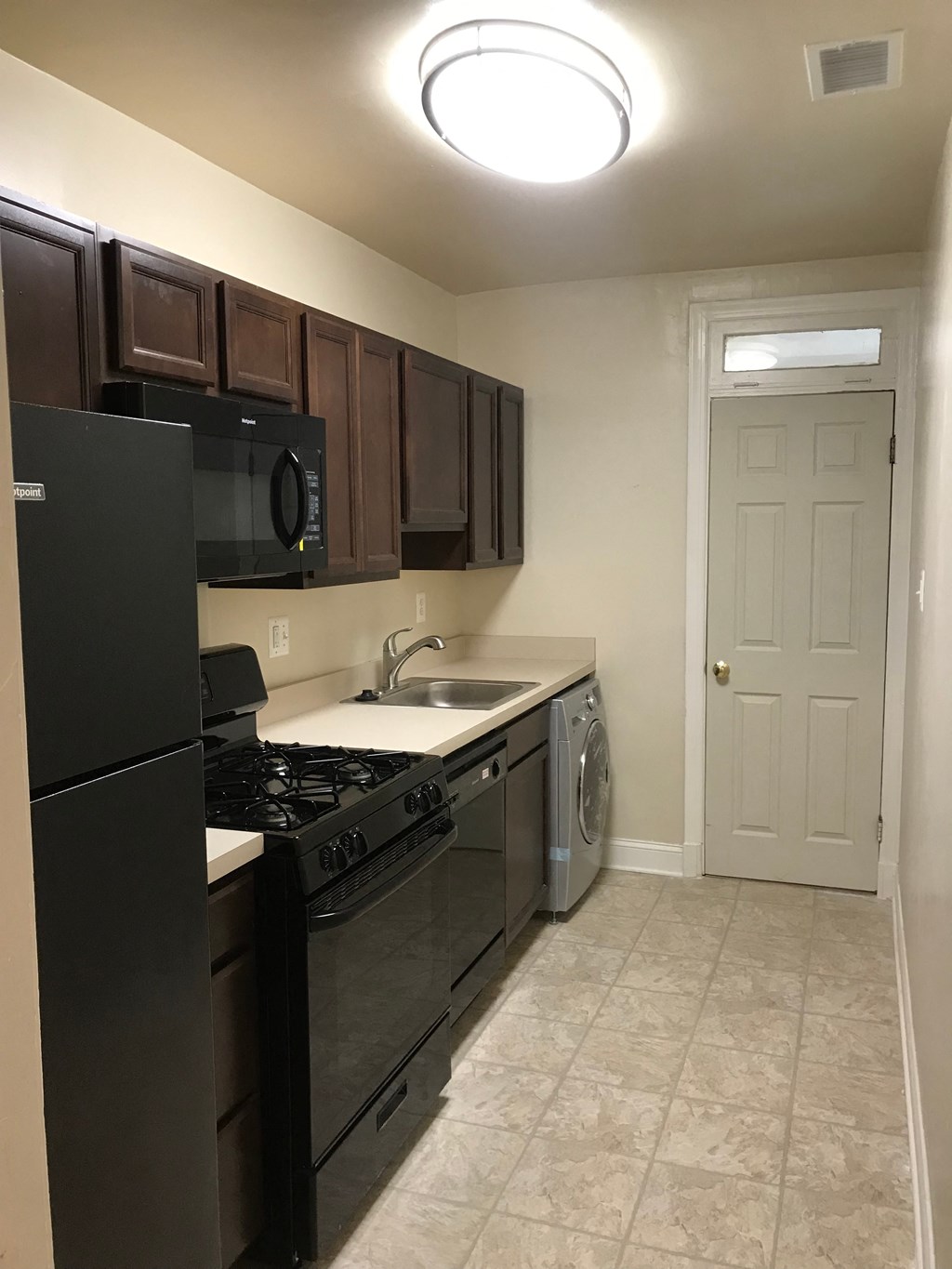 A kitchen with black appliances and brown cabinets.