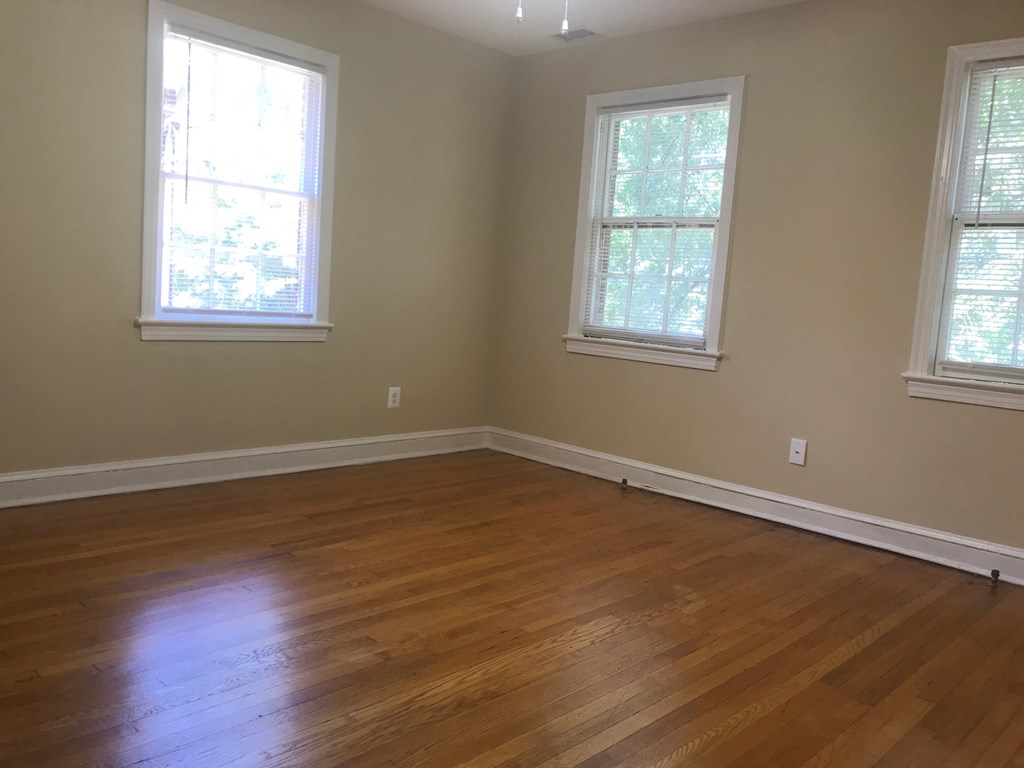 A room with wooden floors and three windows.