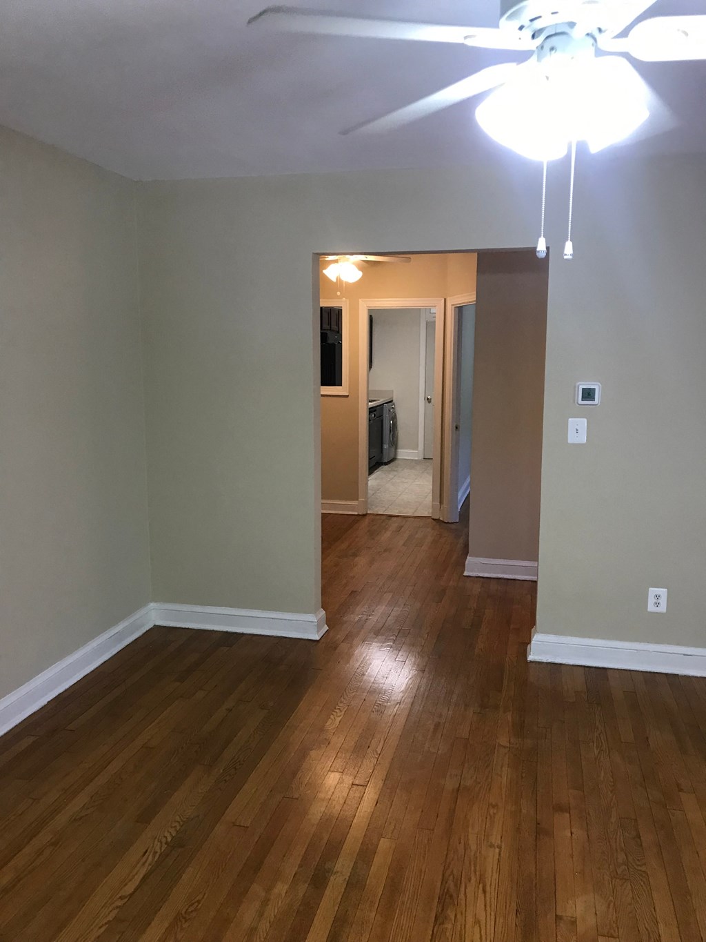 A room with a ceiling fan and wooden floors.