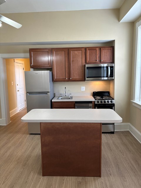 A kitchen with a white counter top and brown cabinets.