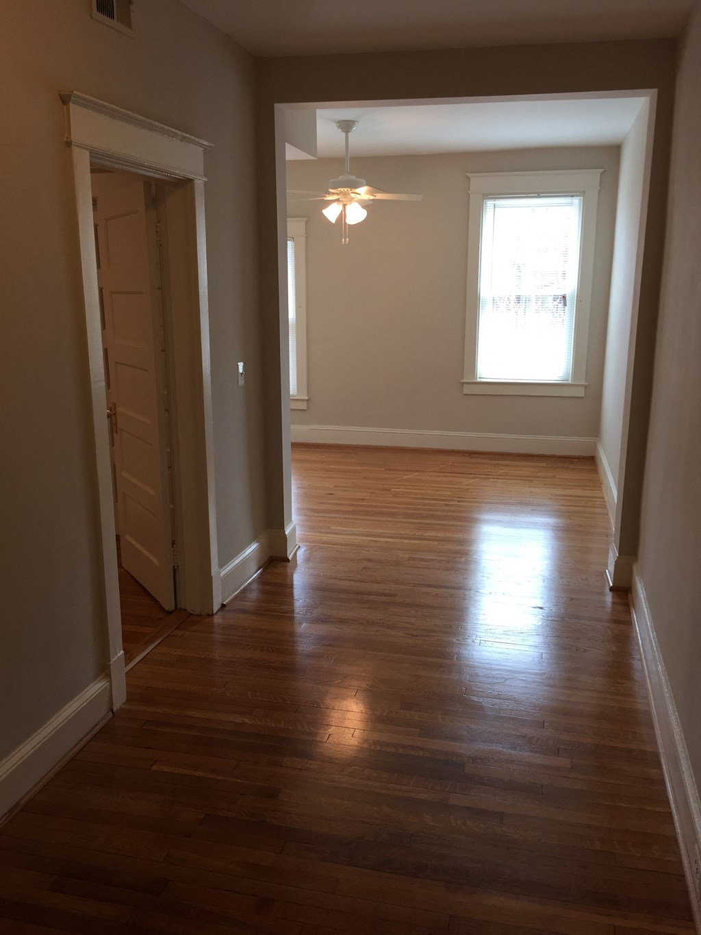 A long hallway with a wooden floor and a light on.