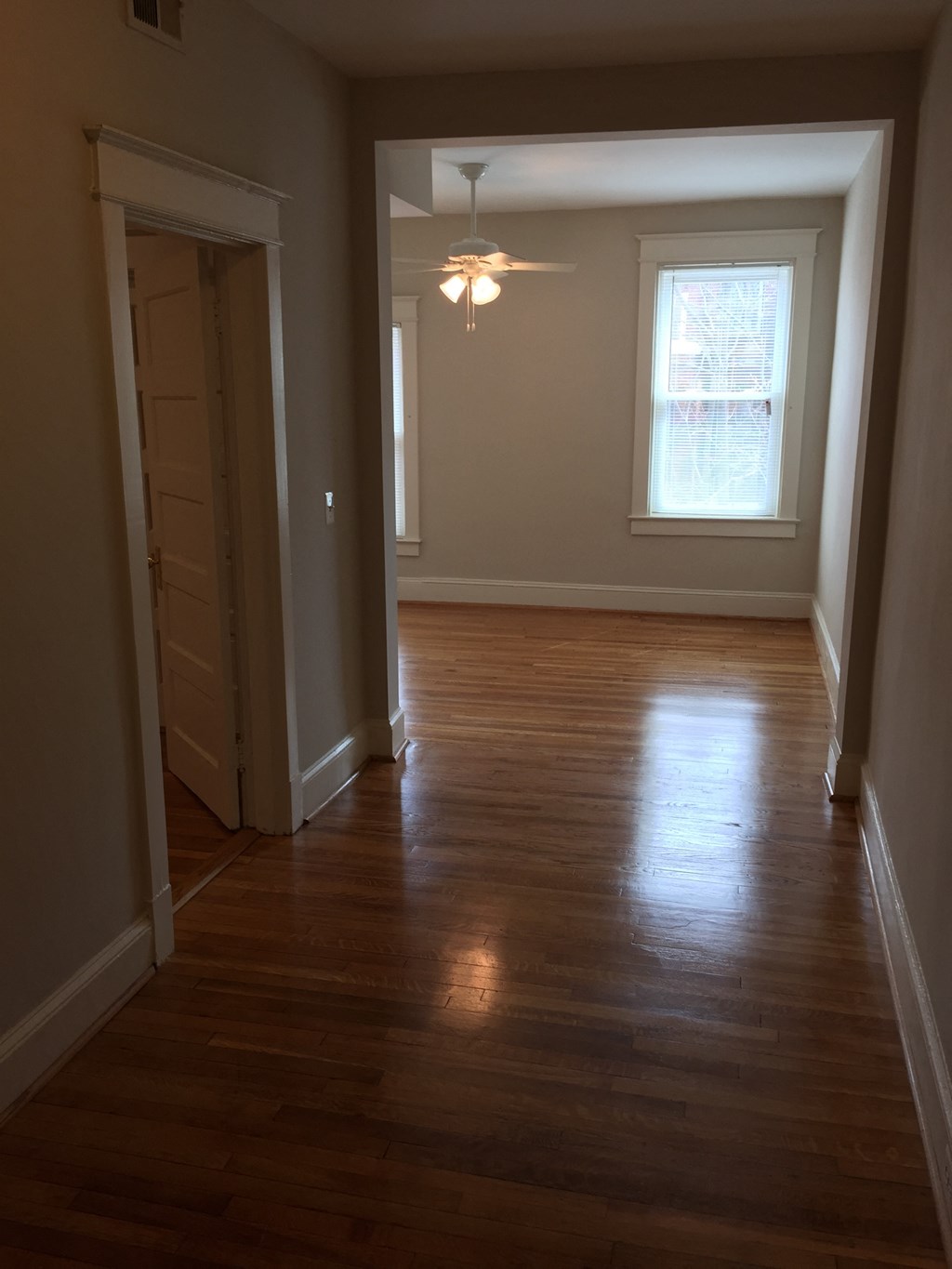 A long hallway with wood floors and a light on.