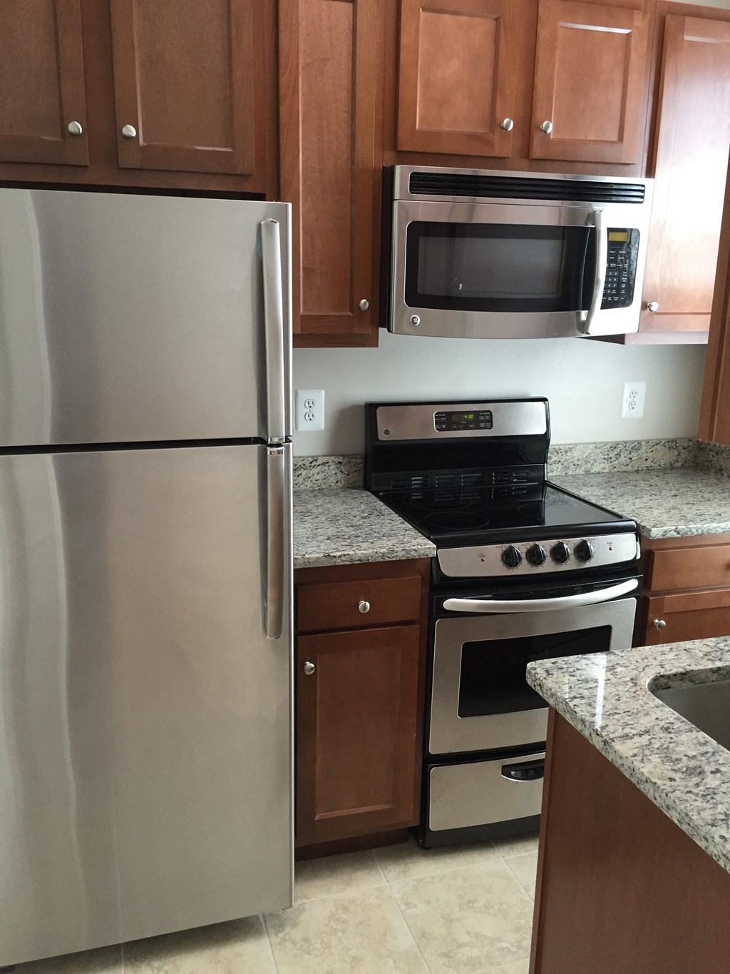 A kitchen with a refrigerator, oven, microwave, and cabinets.