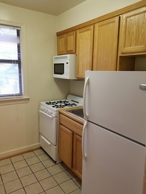 A kitchen with a white refrigerator, white stove, and white microwave.