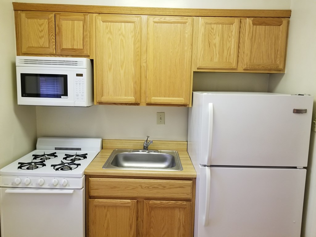 A kitchen with a white stove, white refrigerator, and wooden cabinets.