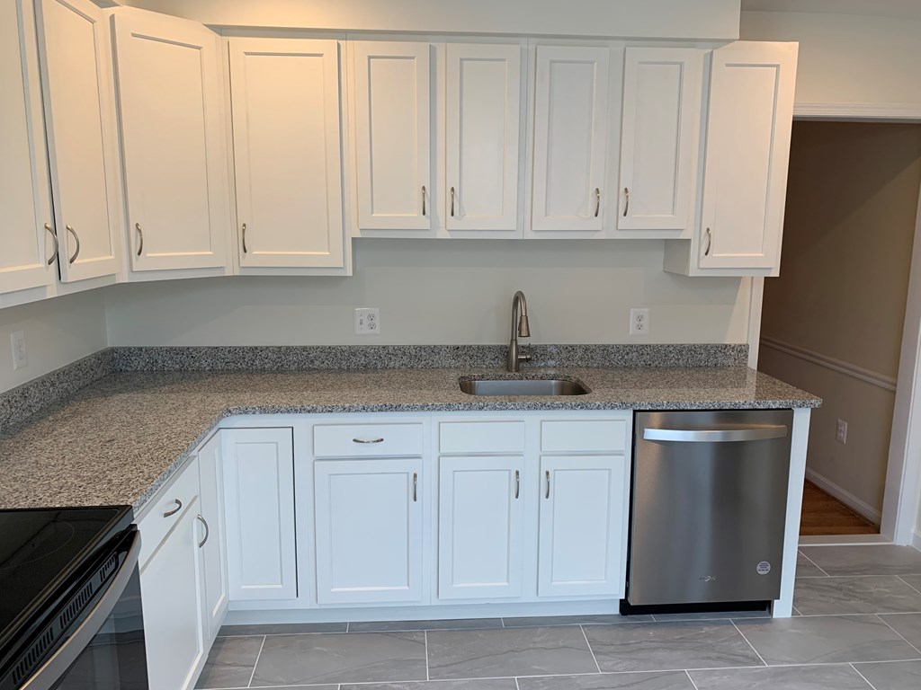 A kitchen with white cabinets and a granite countertop.