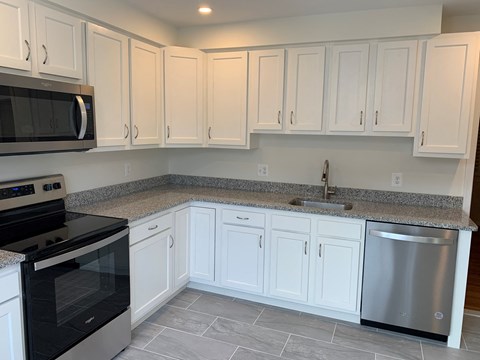 A kitchen with white cabinets and a black stove top oven.