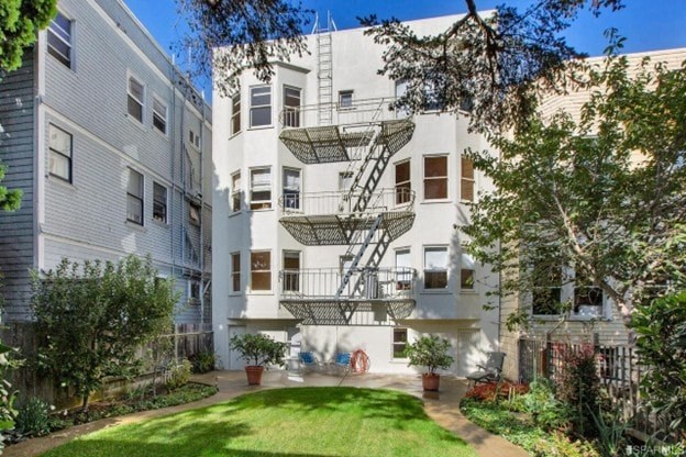A white apartment building with a green lawn in front.