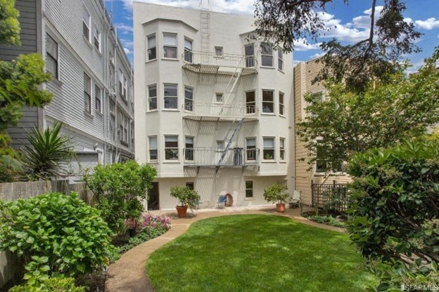 A white apartment building with a green lawn in front.