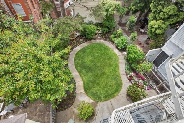 A small, well-kept garden with a grassy area and a variety of plants.