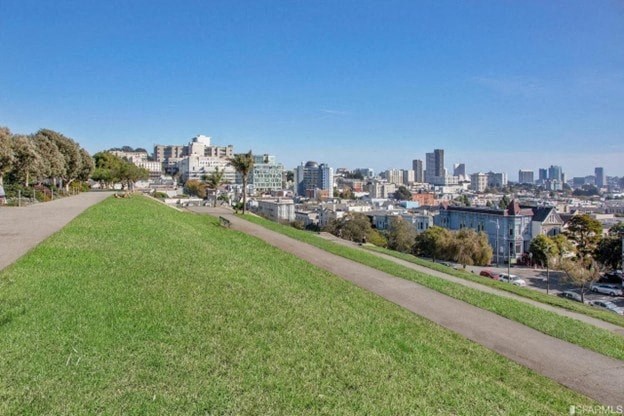 A park with a pathway and a city skyline in the background.