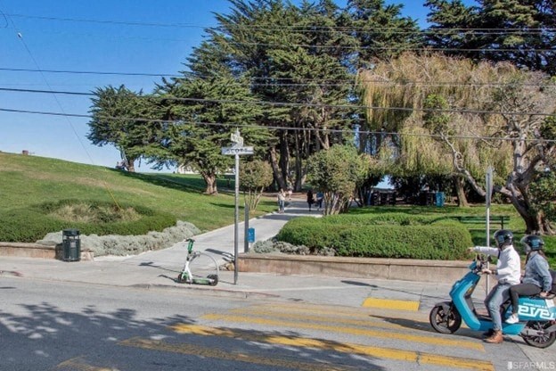 Two people riding a blue scooter on a street.