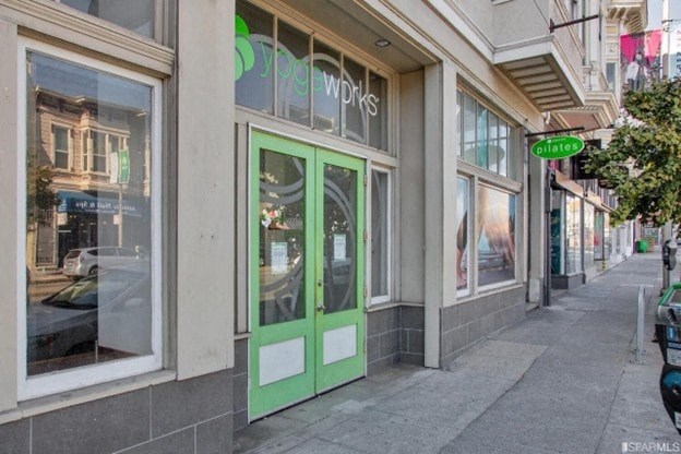 A storefront with a green door and window with a reflection of a car.