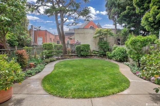 A backyard with a green lawn and a concrete walkway.