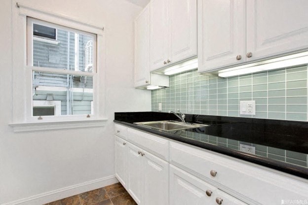 A kitchen with white cabinets and a black countertop.