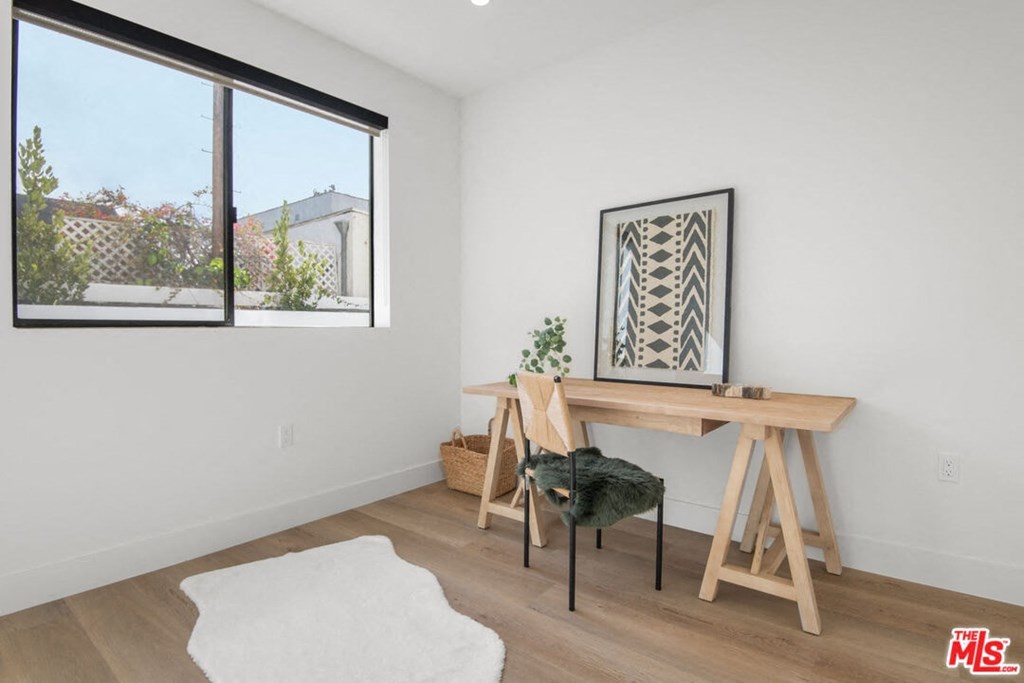 a home office with a desk and a large window