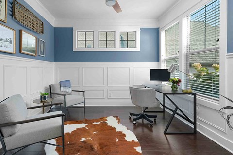a living room with chairs and a desk with a computer