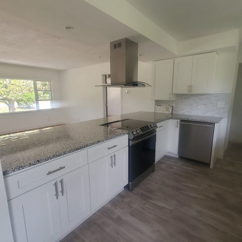 A kitchen with white cabinets and a granite countertop.