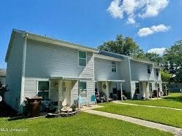 A white two-story house with a blue sky and clouds in the background.