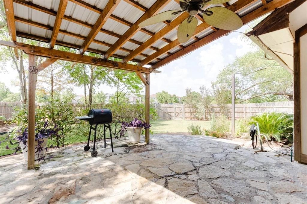 a covered patio with a grill and a fan