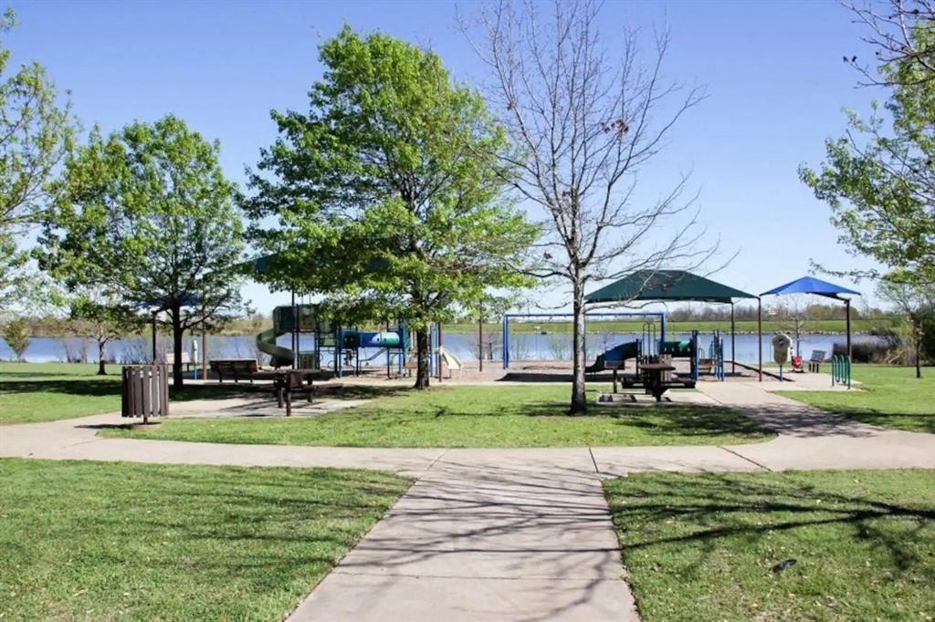 a park with picnic tables and umbrellas next to a lake