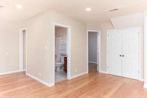 a living room with a hard wood floor and a door into a bathroom