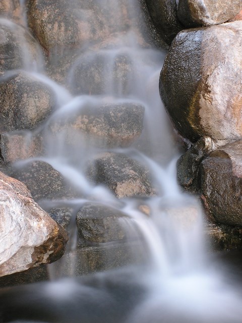 A small waterfall cascades over a rocky surface.