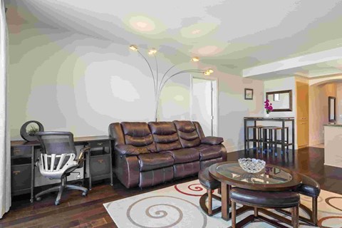 A living room with a brown leather couch and a glass coffee table.