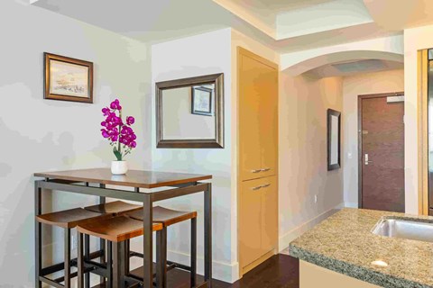 A kitchen with a table and chairs and a vase of flowers.