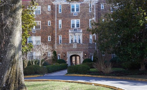 A large brick building with a tree in the foreground.