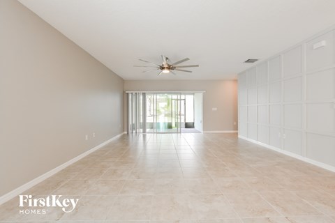 a spacious living room with tile flooring and a ceiling fan
