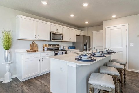 A kitchen with white cabinets and a large island with four stools.