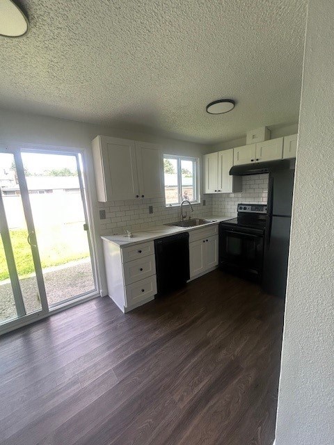 A kitchen with white cabinets and black appliances.