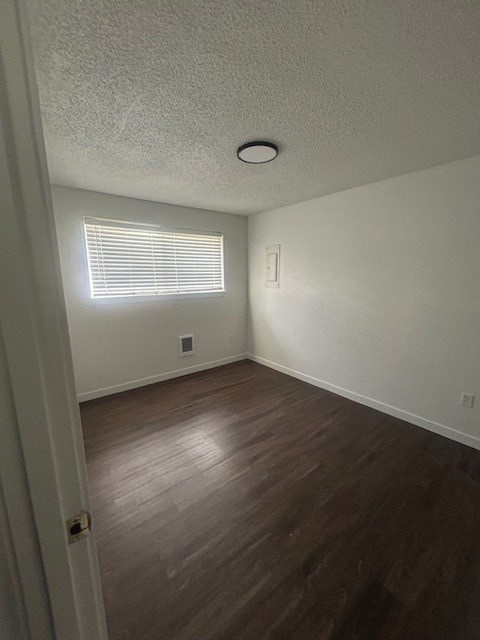 A room with a wooden floor and a window with blinds.