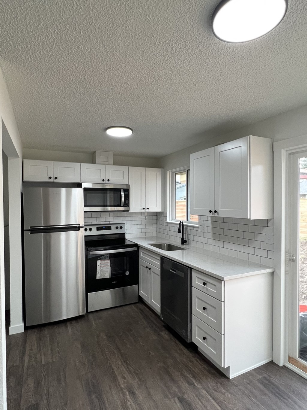 A modern kitchen with a refrigerator, oven, and microwave.
