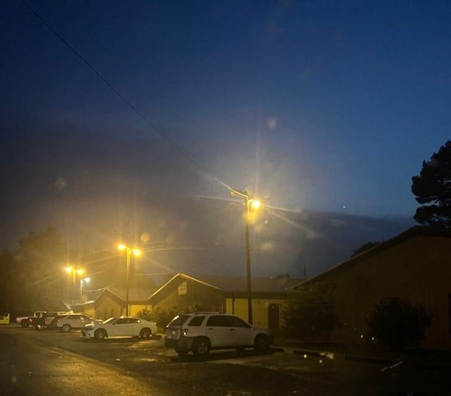 A car is parked in a parking lot at night.